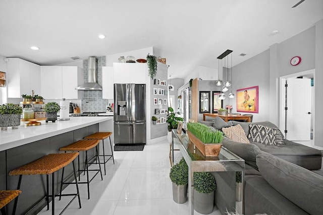 1550 SW 194th Ave, Pembroke Pines, FL 33029 - kitchen featuring wall chimney range hood, stainless steel refrigerator with ice dispenser, a kitchen breakfast bar, light countertops, and white cabinets