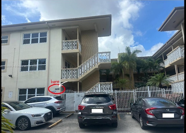 view of building exterior featuring fence and uncovered parking