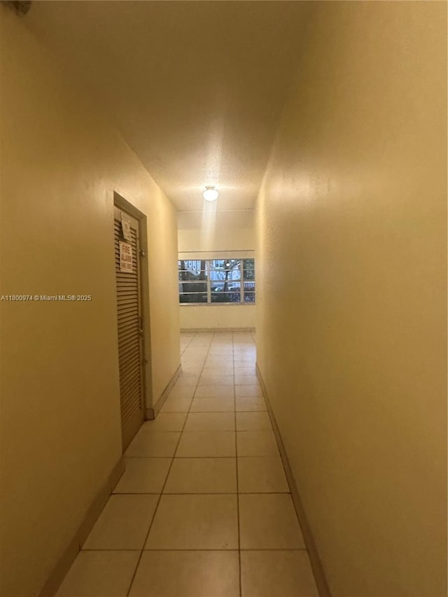 corridor with light tile patterned floors and baseboards