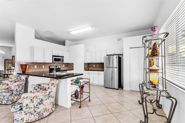 2819 Augusta Ln, Homestead, FL 33035 - kitchen featuring appliances with stainless steel finishes, a peninsula, light tile patterned floors, and tasteful backsplash