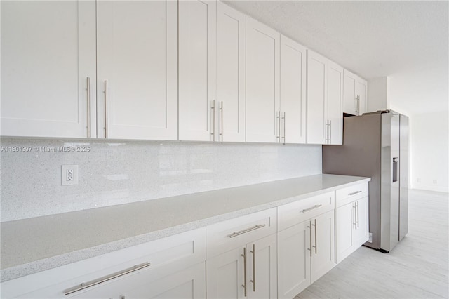 6381 Willoughby Cir, Lake Worth, FL 33463 - kitchen featuring white cabinetry, decorative backsplash, stainless steel refrigerator with ice dispenser, light wood finished floors, and light stone counters