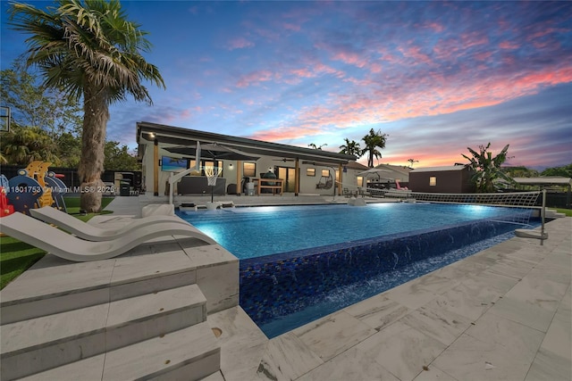 8840 SW 181st Ter, Palmetto Bay, FL 33157 - pool at dusk featuring a patio, an infinity pool, fence, and a ceiling fan