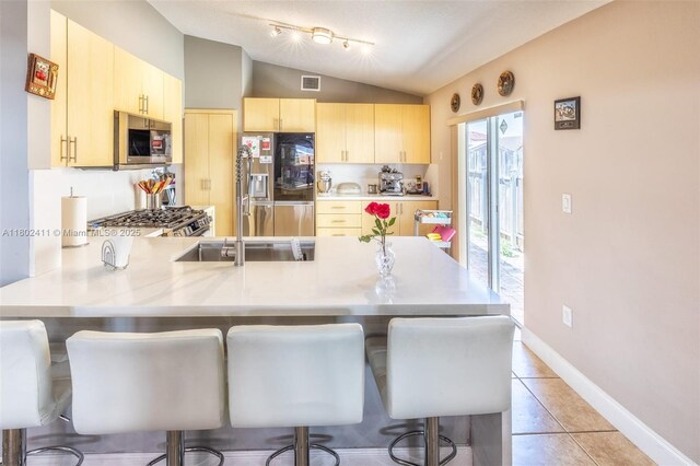 15763 SW 82nd St, Miami, FL 33193 - kitchen with appliances with stainless steel finishes, a peninsula, light brown cabinetry, lofted ceiling, and a breakfast bar area