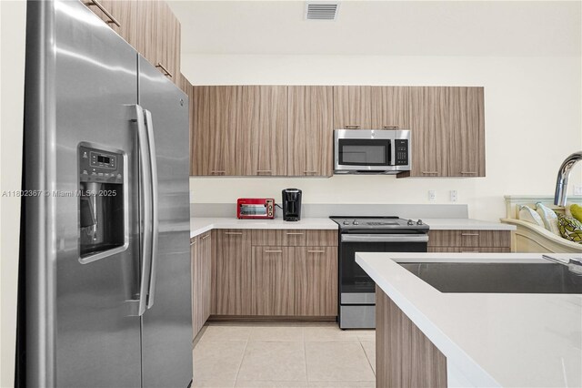 8301 NW 41st St Unit B-303, Doral, FL 33166 - kitchen with appliances with stainless steel finishes, light countertops, light tile patterned floors, modern cabinets, and a sink