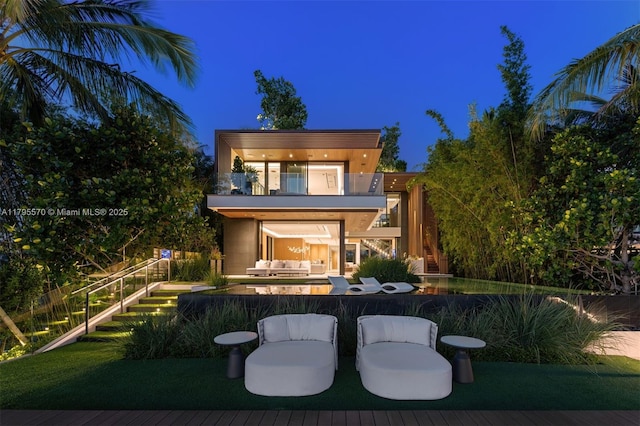 220 W Dilido Dr, Miami Beach, FL 33139 - back of house at twilight with a balcony, an outdoor living space, and a patio area