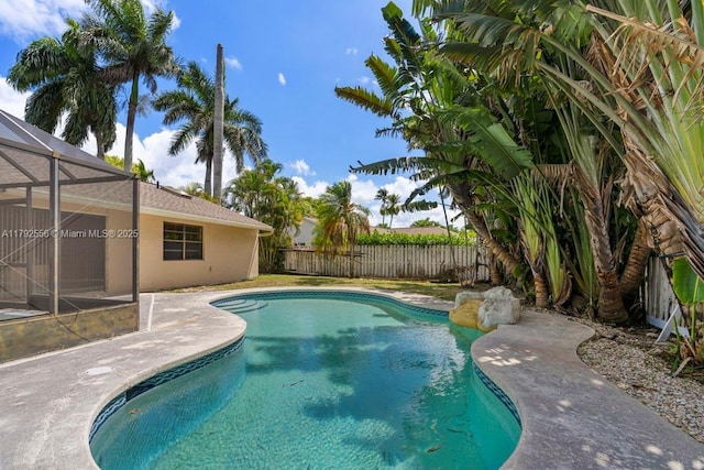 view of swimming pool with a fenced backyard, a patio, and glass enclosure