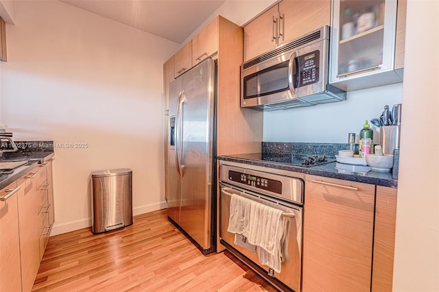 31 SE 5th St Unit 1603, Miami, FL 33131 - kitchen featuring appliances with stainless steel finishes, light wood finished floors, glass insert cabinets, baseboards, and dark stone counters