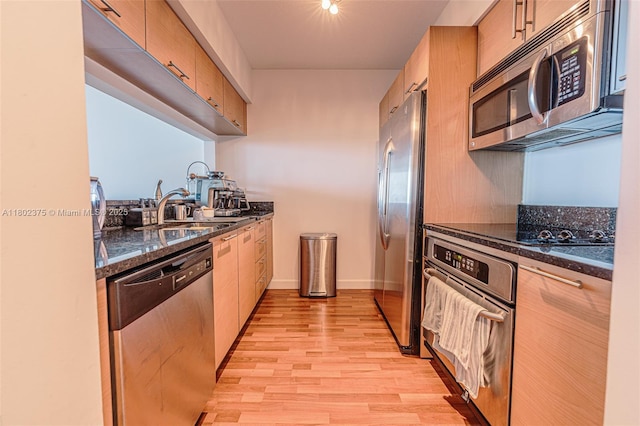 31 SE 5th St Unit 1603, Miami, FL 33131 - kitchen featuring appliances with stainless steel finishes, a sink, light wood-style floors, dark stone countertops, and baseboards