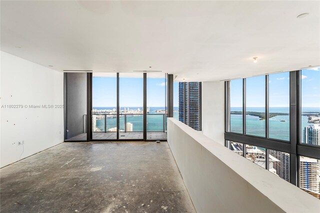 1000 Brickell Plz Unit Uph6201, Miami, FL 33131 - empty room featuring a water view, a wall of windows, healthy amount of natural light, and concrete floors