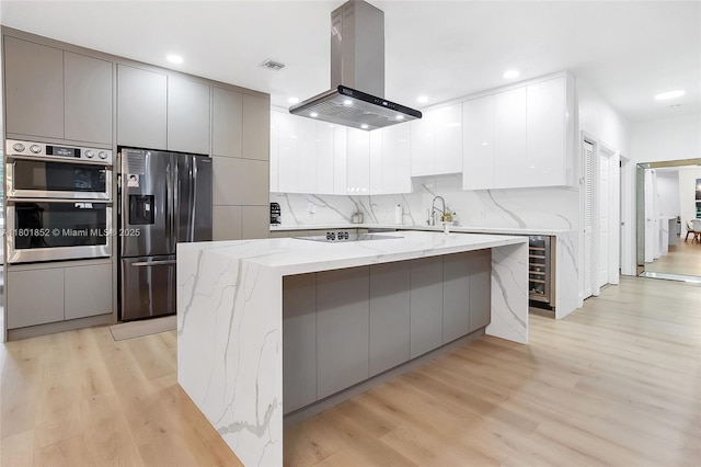 5530 SW 195th Ter, Southwest Ranches, FL 33332 - kitchen with appliances with stainless steel finishes, island range hood, modern cabinets, light wood finished floors, and recessed lighting