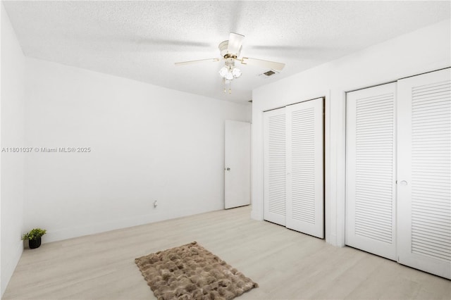5706 NW 81st Ave, Tamarac, FL 33321 - unfurnished bedroom featuring two closets, wood finished floors, a textured ceiling, and a ceiling fan
