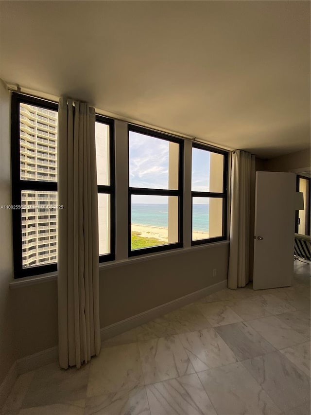 empty room with baseboards and marble look tile flooring