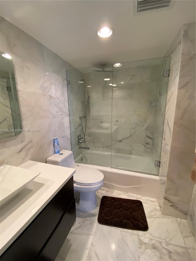 full bath with marble look tile flooring, a combined bath / shower with rainfall shower, tile walls, vanity, and toilet