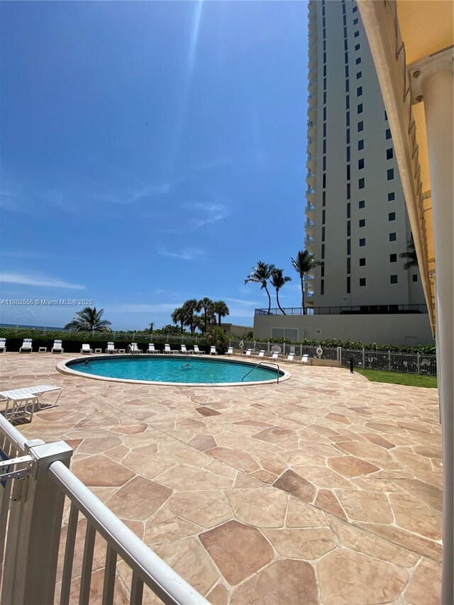 community pool with a patio and fence