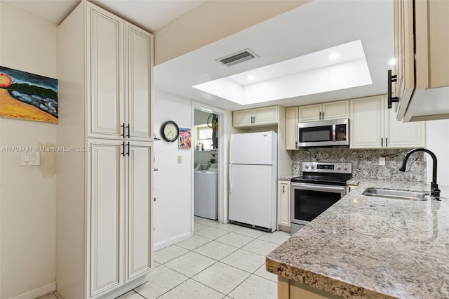 4216 NW 52nd Ave, Lauderdale Lakes, FL 33319 - kitchen with stainless steel appliances, a sink, washer / clothes dryer, a tray ceiling, and baseboards