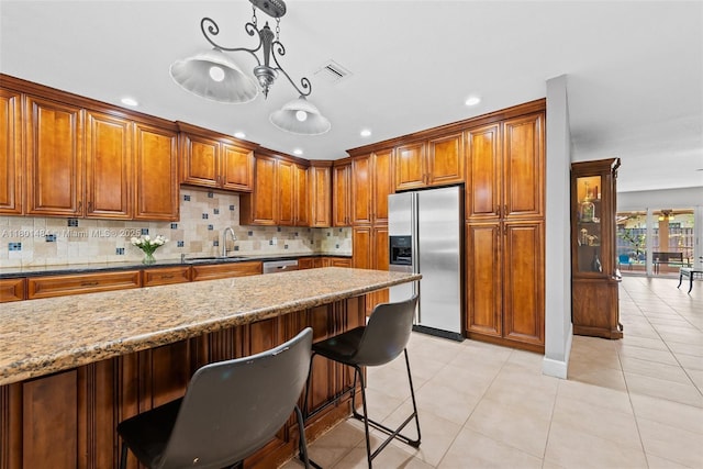 2426 NW 91st Ave, Coral Springs, FL 33065 - kitchen featuring appliances with stainless steel finishes, brown cabinetry, a sink, a kitchen bar, and recessed lighting