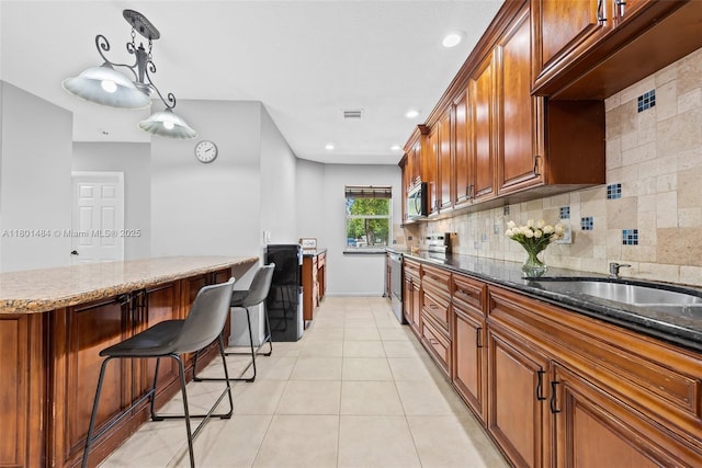 2426 NW 91st Ave, Coral Springs, FL 33065 - kitchen featuring appliances with stainless steel finishes, a sink, dark stone counters, brown cabinetry, and recessed lighting