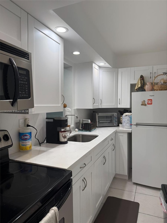 1720 NW N River Dr Unit 203, Miami, FL 33125 - kitchen featuring freestanding refrigerator, electric range oven, stainless steel microwave, a sink, and white cabinets