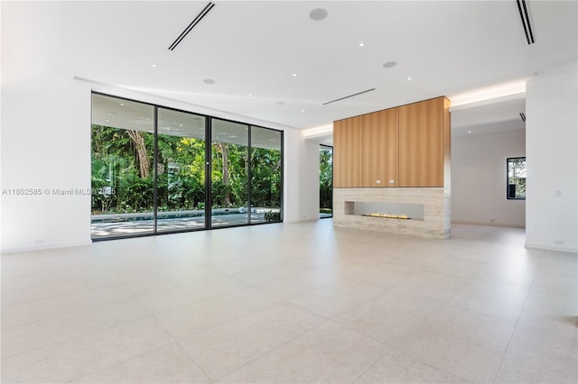 unfurnished living room with expansive windows, a fireplace, and light tile patterned floors