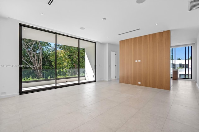 spare room featuring expansive windows and light tile patterned flooring