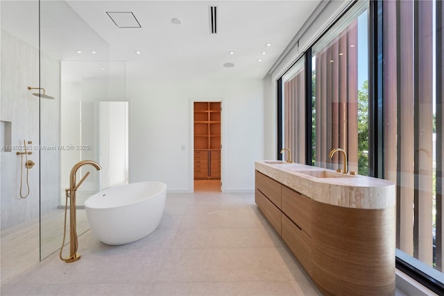 bathroom featuring a freestanding bath, double vanity, a walk in shower, and tile patterned flooring