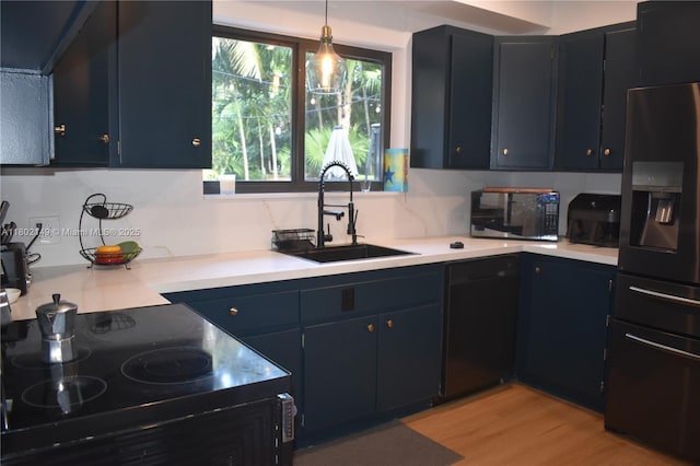 465 NE 52nd St, Miami, FL 33137 - kitchen featuring black appliances, a sink, light countertops, light wood-style floors, and pendant lighting
