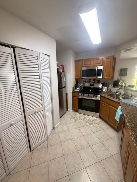 3437 NW 44th St Unit 101, Oakland Park, FL 33309 - kitchen with appliances with stainless steel finishes, a sink, light tile patterned floors, and brown cabinetry