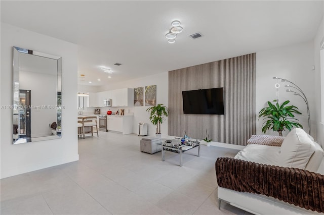 living area featuring baseboards and an accent wall