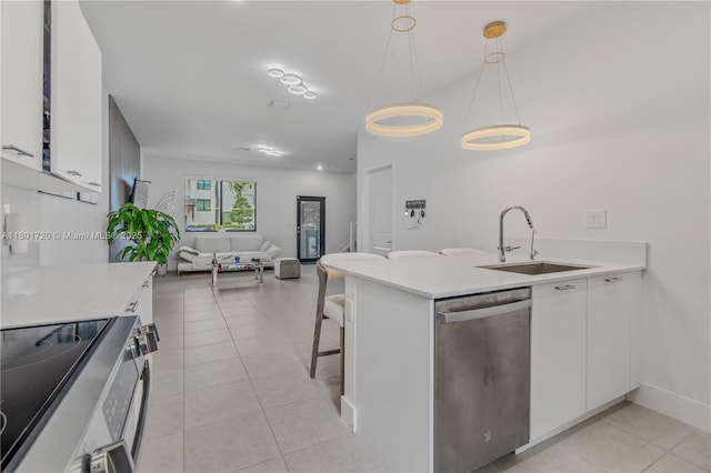 kitchen with appliances with stainless steel finishes, a sink, open floor plan, and light countertops