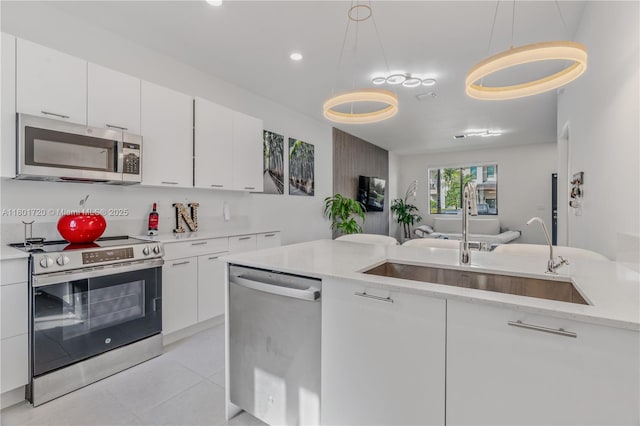 kitchen featuring appliances with stainless steel finishes, a sink, white cabinetry, open floor plan, and recessed lighting