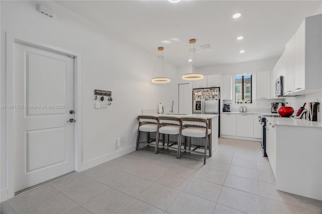 kitchen with stainless steel appliances, a peninsula, a breakfast bar area, recessed lighting, and light countertops