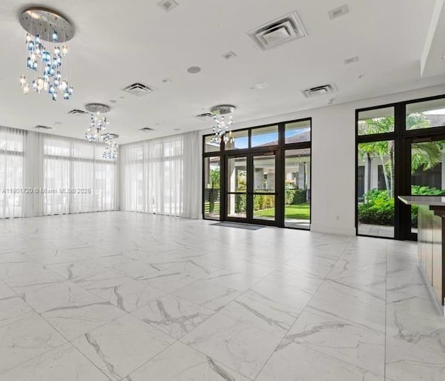 unfurnished room featuring a chandelier and light marble finish floors