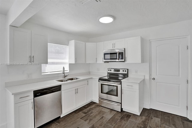 242 SW 9th St, Dania Beach, FL 33004 - kitchen with appliances with stainless steel finishes, a sink, white cabinetry, dark wood-style floors, and light countertops