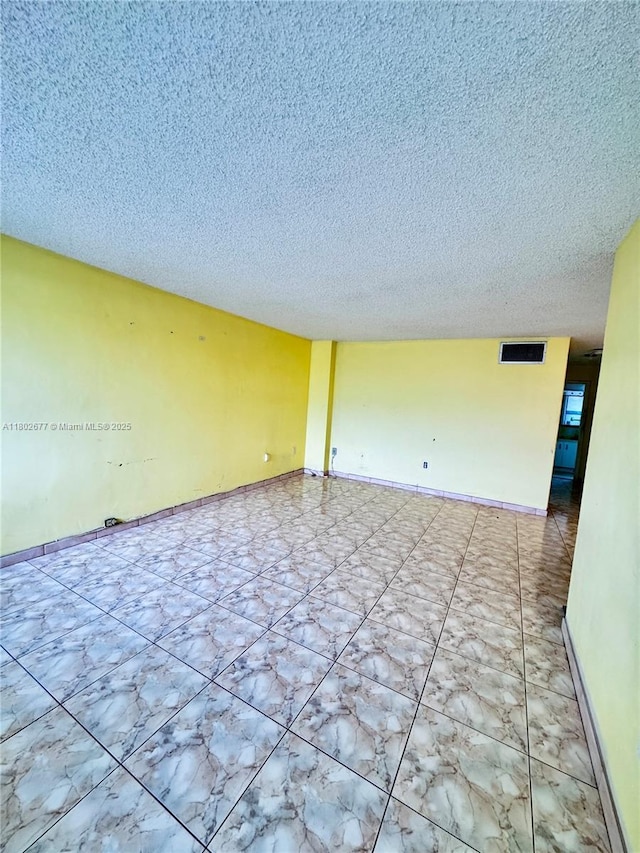 unfurnished room featuring a textured ceiling and baseboards