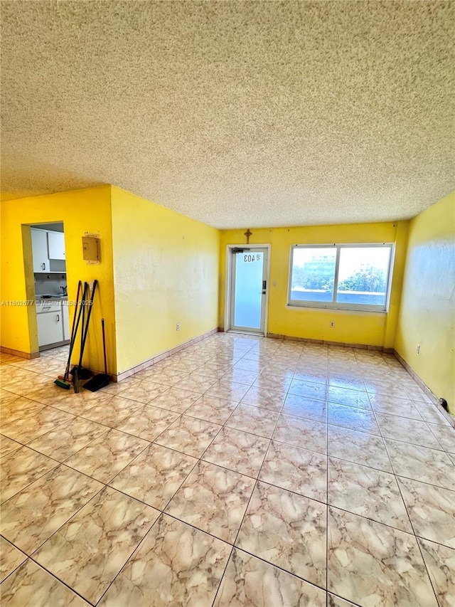 empty room featuring a textured ceiling and baseboards