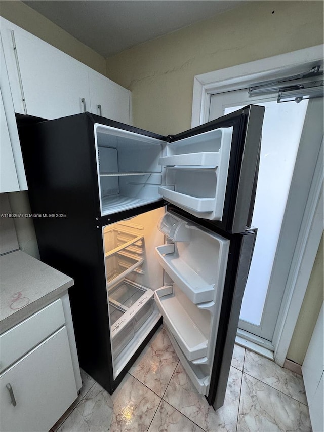 kitchen view of refrigerator, white cabinets, and light countertops