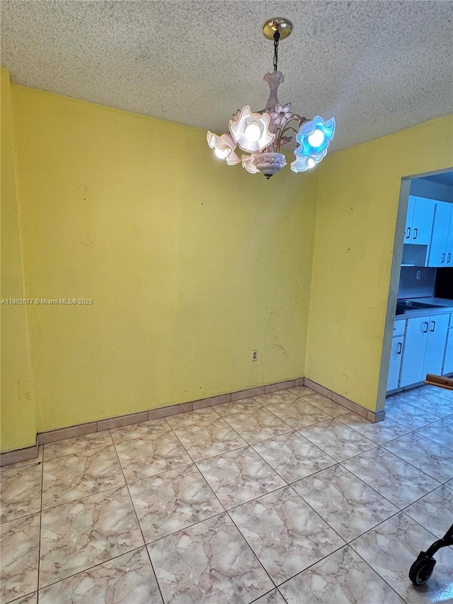 unfurnished room with a chandelier and a textured ceiling