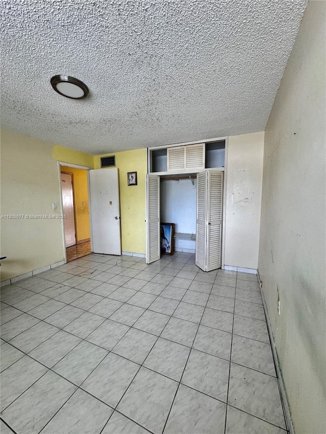 unfurnished bedroom featuring a textured ceiling, a closet, and baseboards