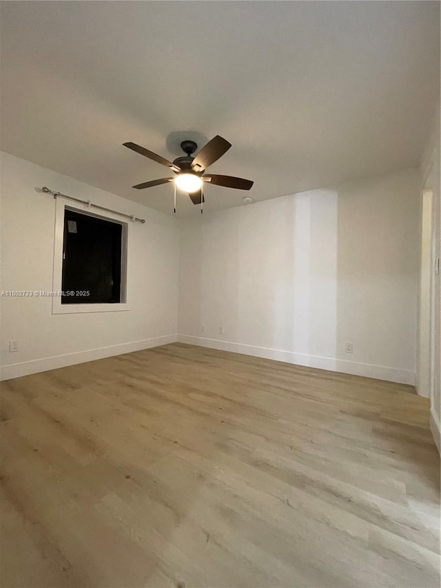 empty room featuring light wood-style flooring, a ceiling fan, and baseboards