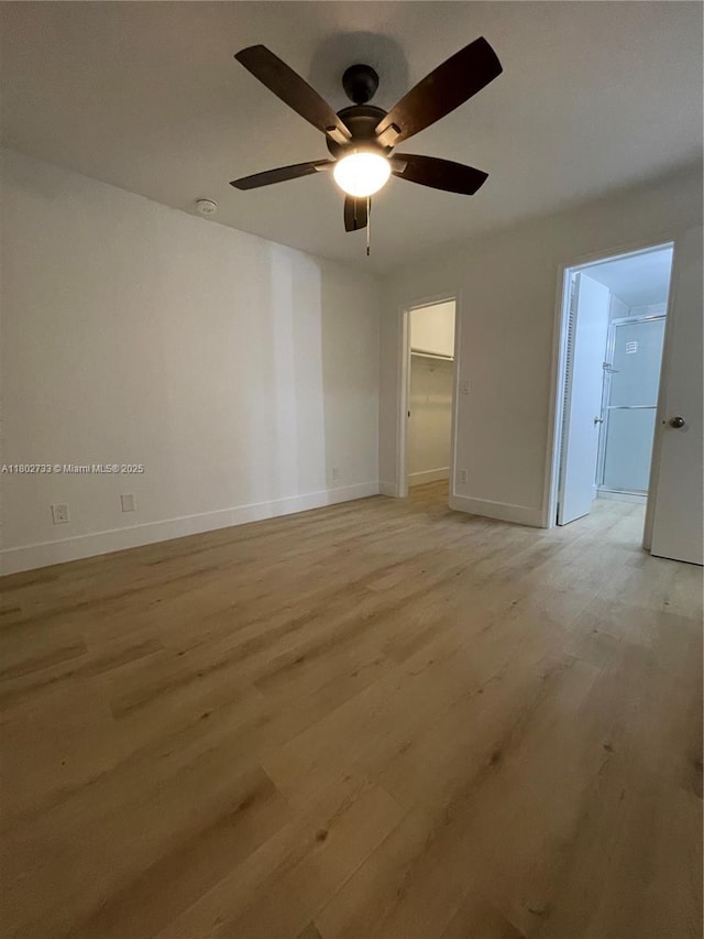 spare room featuring light wood-style flooring, a ceiling fan, baseboards, and a smoke detector