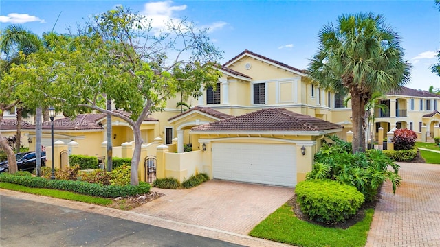 1504 Passion Vine Cir Unit 23-4, Weston, FL 33326 - mediterranean / spanish house featuring decorative driveway, stucco siding, a tiled roof, a fenced front yard, and an attached garage