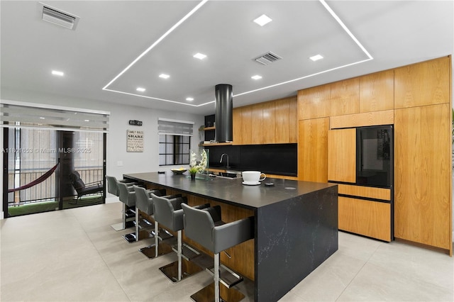 1504 Passion Vine Cir Unit 23-4, Weston, FL 33326 - kitchen featuring dark countertops, a kitchen breakfast bar, a center island with sink, open shelves, and island range hood