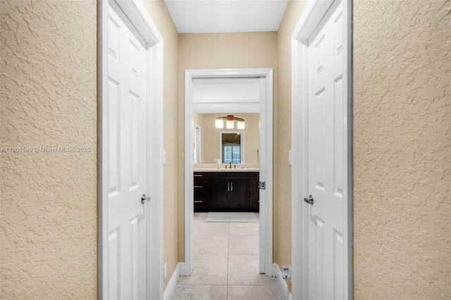 1708 NW 126th Dr, Coral Springs, FL 33071 - hallway with light tile patterned flooring, a textured wall, baseboards, and a sink