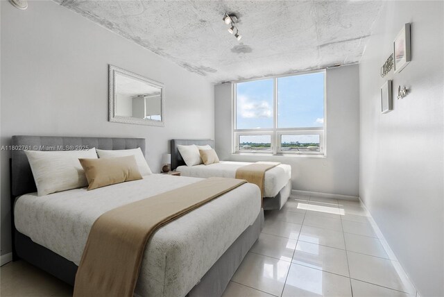 3250 NE 1st Ave Unit 706, Miami, FL 33137 - bedroom featuring baseboards, light tile patterned floors, and track lighting
