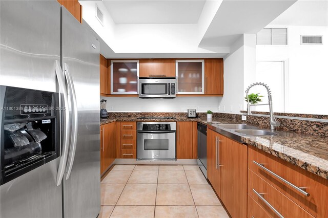 888 S Douglas Rd Unit 910, Coral Gables, FL 33134 - kitchen with appliances with stainless steel finishes, brown cabinets, dark stone countertops, and glass insert cabinets