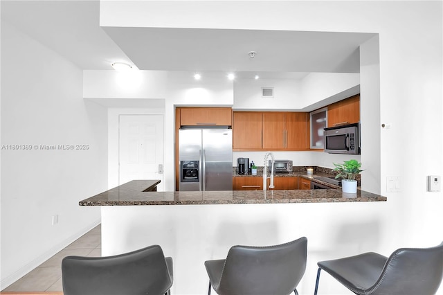 888 S Douglas Rd Unit 910, Coral Gables, FL 33134 - kitchen with appliances with stainless steel finishes, brown cabinets, light tile patterned flooring, a peninsula, and a kitchen bar
