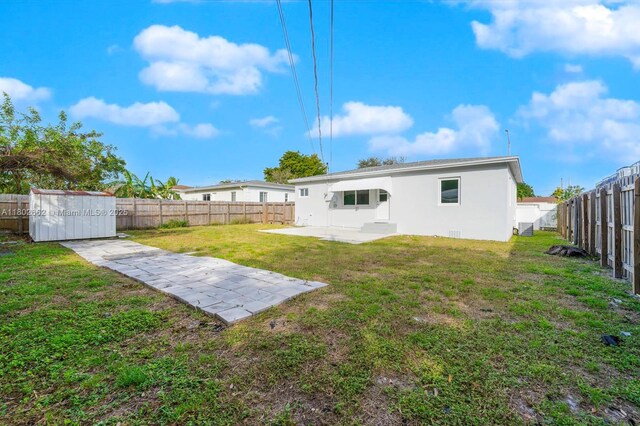 1980 NE 159th St, North Miami Beach, FL 33162 - rear view of property featuring a patio area, stucco siding, a storage unit, and an outdoor structure