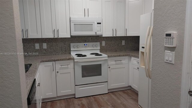 1165 Golden Lakes Blvd Unit 1221, West Palm Beach, FL 33411 - kitchen with white appliances, white cabinetry, a textured wall, light stone countertops, and wood finished floors