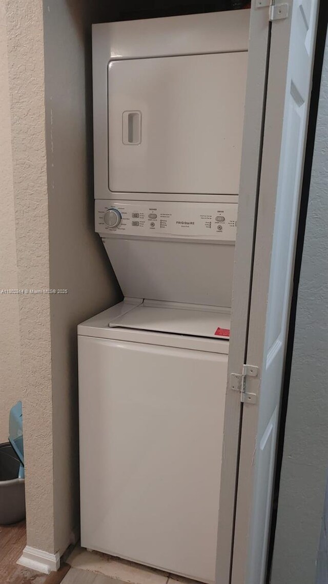 1165 Golden Lakes Blvd Unit 1221, West Palm Beach, FL 33411 - washroom featuring stacked washer / dryer, light wood-type flooring, and a textured wall