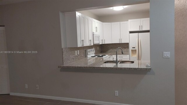 1165 Golden Lakes Blvd Unit 1221, West Palm Beach, FL 33411 - kitchen with white appliances, tasteful backsplash, light stone counters, white cabinets, and a peninsula